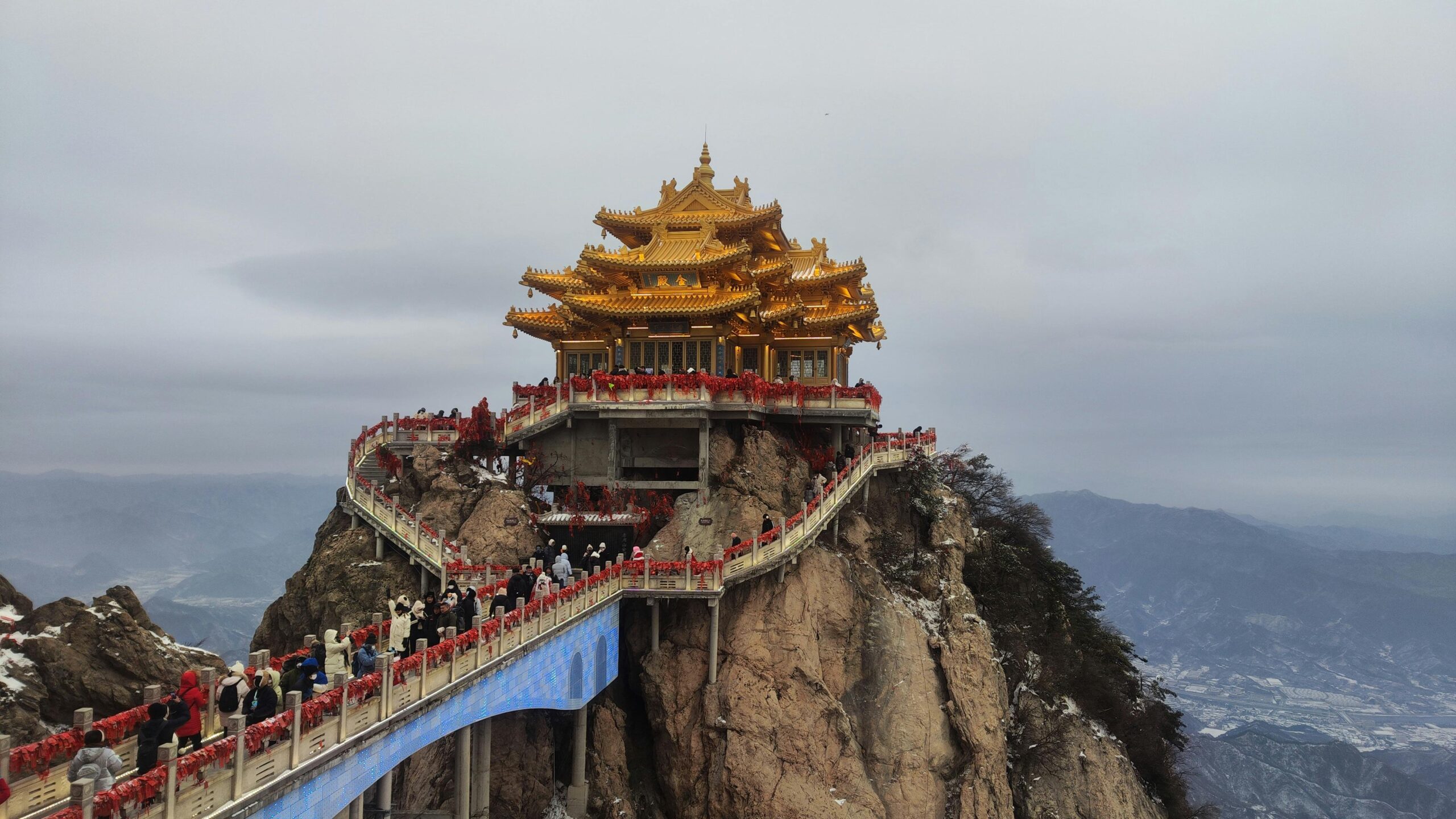 Golden temple atop Mount Tai with scenic views and crowds walking uphill.