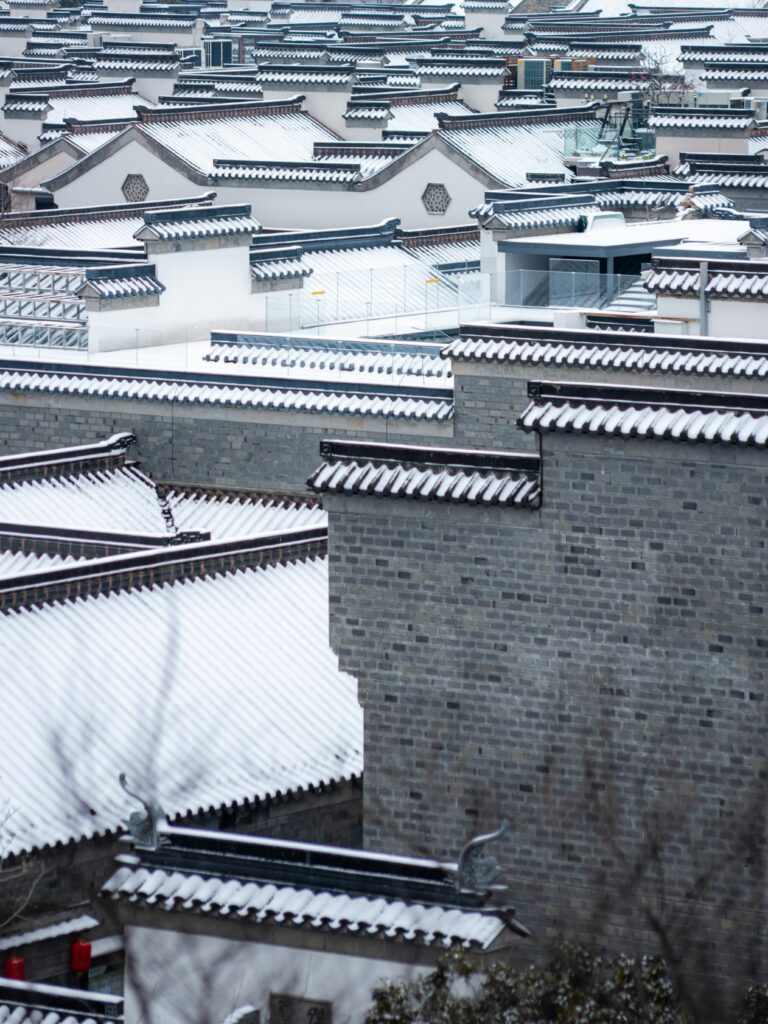 China Cultural Insights - Snow blankets traditional Chinese rooftops in a serene winter scene.